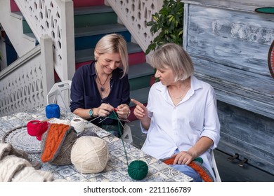 Mom And Daughter Knit Together In The Garden. Family Friendly Leisure. Elderly Mother Teaching To Crochet Adult Daughter 