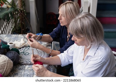 Mom And Daughter Knit Together In The Garden. Family Friendly Leisure. Elderly Mother Teaching To Crochet Adult Daughter 