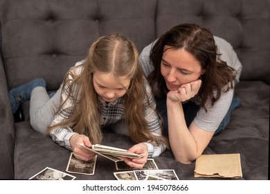 Mom And Daughter Are Lying On The Couch And Looking At The Family Photo Archive. Family, Trust, Succession Concept.