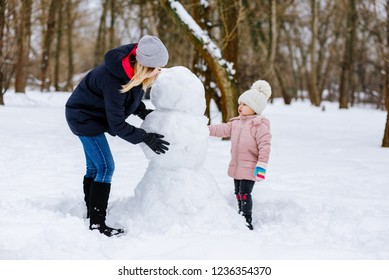 Mom And Daughter Make A Snowman Out Of Snow