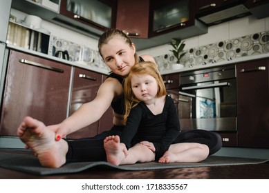 Mom And Daughter On Mat In Yoga Pose At Home. Sports Mom With Kid Doing Work-out. Mum, Child Do The Exercises, Healthy Family. Fitness. Calmness Concept. Coronavirus Stay Home. Trains During Pandemic.