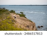 Mom and daughter on a sea cliff on the Paldiski Peninsula on a summer evening, the sky is overcast. 