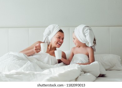 Mom And Daughter On Spa Vacation, Drinking Tea In Bed, White Towels