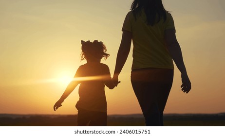 mom and daughter in the park. mom holding her daughter hand walking in the park silhouette at sunset in nature. happy family kid dream concept. mom and kid family walking in nature lifestyle - Powered by Shutterstock