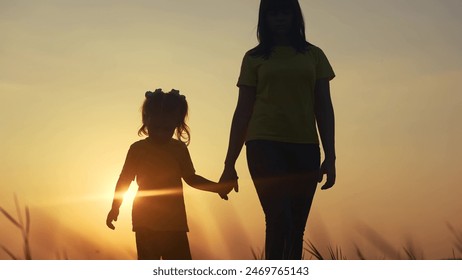 mom and daughter in the park. mom holding her daughter hand walking in the park silhouette at sunset in nature. happy family kid dream concept lifestyle. mom and kid family walking in nature - Powered by Shutterstock