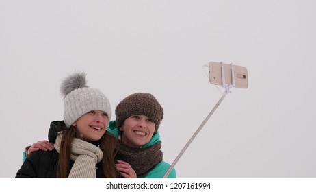 Mom With Daughter, Photograph Selfie On Phone, Winter Snow Park. They Laugh, Smile And Take Pictures.