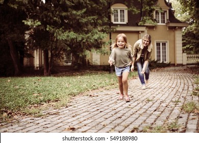 Mom And Daughter Playing In Front Of House.
