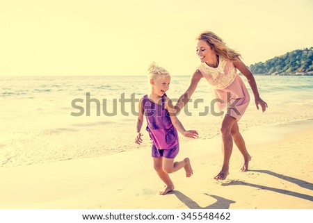 Mom and daughter running on the beach - Family moments, beautiful young mother trying to catch her daughter, having fun and enjoying summer holiday
