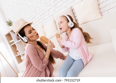 Mom And Daughter Sing Songs At Home. They Use Combs Like Microphones. They Play Together.