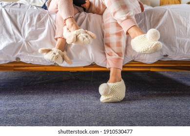 mom and daughter  sitting on bed wearing cute slippers. Cozy homeware mom and toddler. Bonding concept