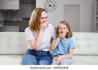 Mom And Daughter Are Sitting On The Couch, They Both Yawn And Want To Sleep. Family Evening Screening Of The Film. Contagious Yawning.