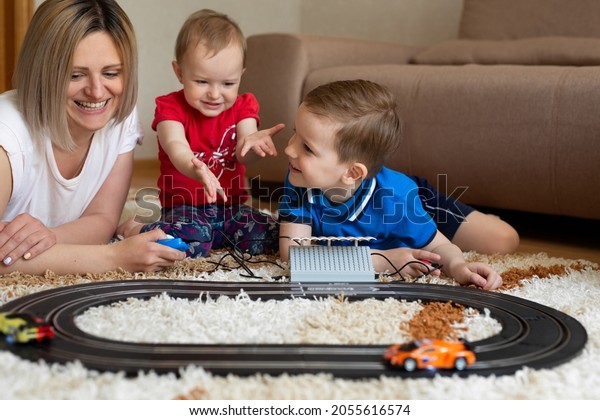 Mom and\
daughter and son play racing on the\
carpet.