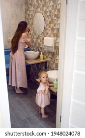 Mom And Daughter Are Standing In The Bathroom Washing Their Hands And Putting On Lipstick. High Quality Photo