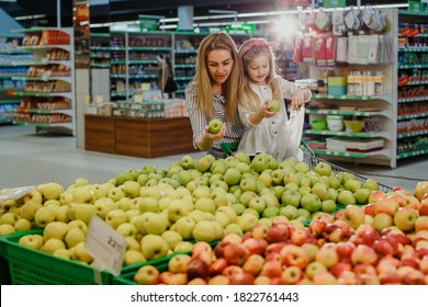 Mom With Daughter In The Supermarket. Girls Choose Fresh Apples. Family Fruit Shopping.