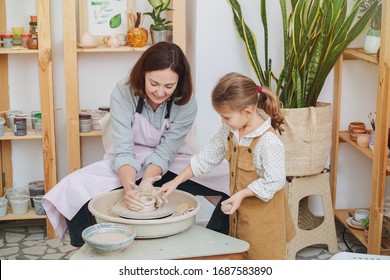 Mom and daughter together, having fun playing with clay make a pot for a potter's wheel in the home studio - Powered by Shutterstock