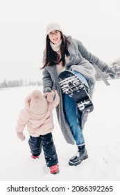 Mom And Daughter In Winter. Happy Family Enjoy Winter Snowy Day. They Hug, Laugh, Have Fun, Ride In The Snow And Enjoy The Winter Snowy Weather