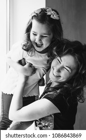 Mom and daughter. Daughter with young mother are laughing. Happy family. Happy mother's day. Casual lifestyle. Black and white photo. Amazing women. Mother tickling daughter.
