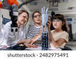 Mom and daughters during take your kid to work day, encouraging them in career in robotics. Field trip to real robotics laboratory. Real scientist talking to girls, showing prosthetic robot hand.