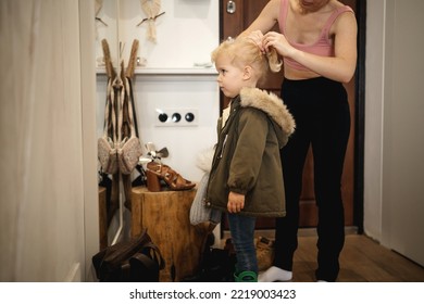 Mom Does Her Child's Hair Before Going Out In The Hallway Of The House In Front Of A Mirror.