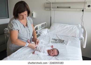 Mom dresses her newborn baby in the maternity hospital bed - Powered by Shutterstock