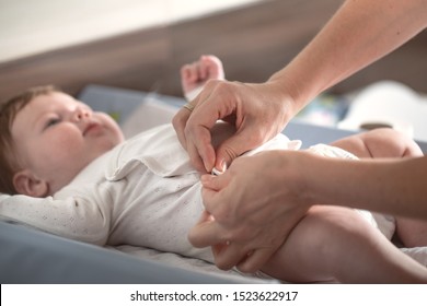 Mom dresses a newborn baby on the changing table . Concept of newborn babies . Close up.
