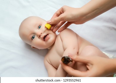 Mom Drops Her Nose To A Newborn Baby. Sick Child, Baby Staying In Bed, Mom Giving Him Medicine And Checking For Fever. Sick Infant.