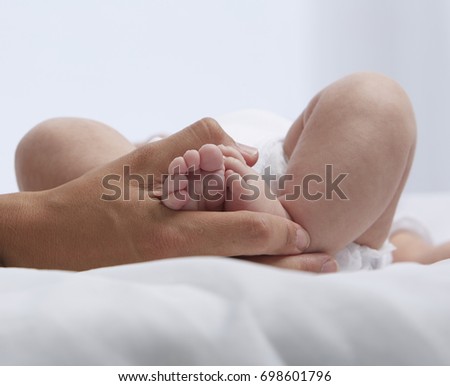 Mom embracing newborn feet.