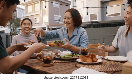 Mom enjoy thai meal cooking for family day home dining at dine table cozy patio. Mum passing serving food to group four asia people young adult man woman friend fun joy relax warm night picnic eating. - Powered by Shutterstock