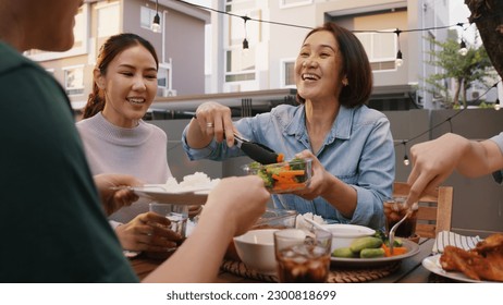 Mom enjoy thai meal cooking for family day home dining at dine table cozy patio. Mum passing serving food to group four asia people young adult man woman friend fun joy relax warm night picnic eating. - Powered by Shutterstock