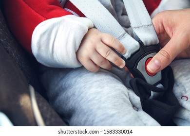 Mom Fastens A Safety Belt In The Car Seat In Which Her Little Child Sits