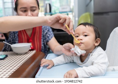 Mom Feeding Her Baby Girl With A Spoon. Mother Giving Food To Her Eight-month Child At Home. Baby Food.