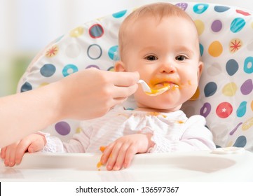 Mom feeds funny baby from a spoon