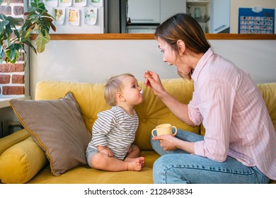 Mom feeds a small child at home with yogurt from a spoon. Family concept - Powered by Shutterstock