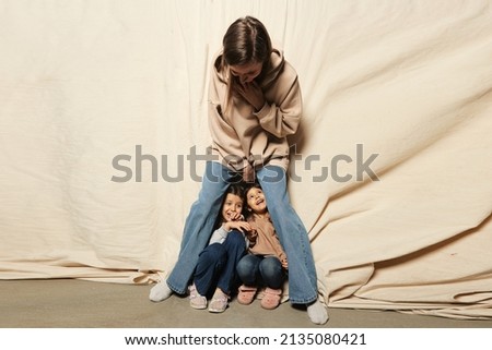 Mom is fooling around and playing with small children. Stylish family in jeans and sweatshirts