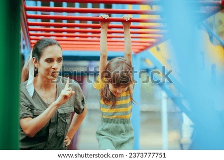 
Mom Forbidding her Child to Climb on a Dangerous Playground Equipment. Caregiver babysitting applying strict safety rules for the little kid
