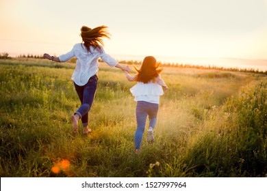 Mom And Girl Running Across The Field. Summer Vacation, Beautiful Sunset.