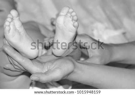 Mom gives baby legs. Black and white close-up photo