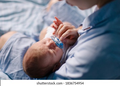 Mom Gives Her Newborn Son A Pacifier. The Mother Calms The Child. The Baby Is Worried About A Tummy Ache. Colic Gases. Nipple. Parenthood. Lull The Kid. Care Tenderness Motherhood  Real Life Lifestyle