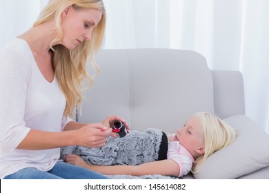 Mom Giving Her Daughter Medicine In The Living Room