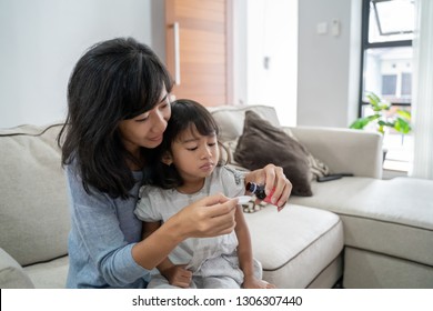 Mom Giving Her Little Girl Some Medicine At Home