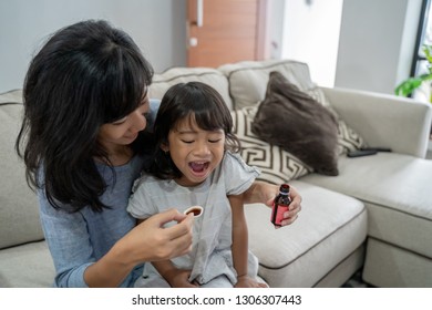 Mom Giving Her Little Girl Some Medicine At Home