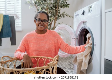 Mom In Glasses Does Household Chores In Bathroom, Laundry Room, Sits On Floor With Wicker Basket Filled With Clothes At Washing Machine, Loads Colorful Things Into Drum, Spinning, Rinsing