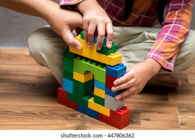 Mom Hand And Asian Kid Girl Building House From Plastic Blocks