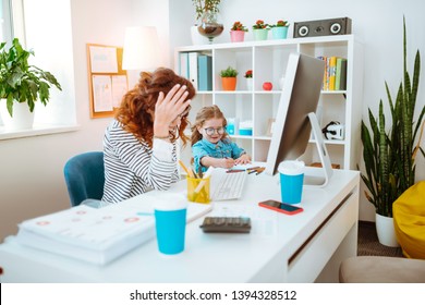 Mom having headache. Young mom having headache while having too much work sitting near daughter playing nearby