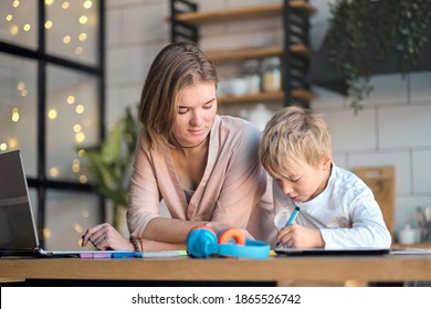 Mom Helping Young Son With Laptop To Do Homework. Young Woman Teaching Little Boy To Use The Computer. Baby Sitter Teaching Little Child Girl Use Laptop Application.