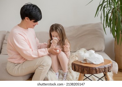 Mom helps her daughter blow her nose. A sick girl having a runny nose using a handkerchief