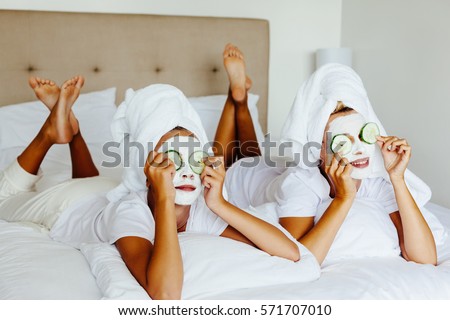 Mom and her 10 years old preteen daughter chilling in the bedroom and making clay facial mask. Mother with child doing beauty treatment together. Morning skin care routine.