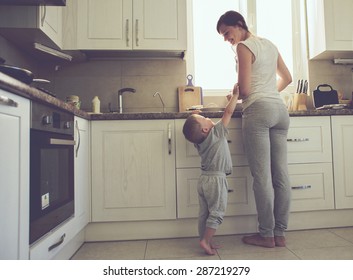 Mom with her 2 years old child cooking holiday pie in the kitchen to Mothers day, casual lifestyle photo series in real life interior - Powered by Shutterstock