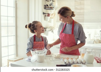 Mom With Her 9 Years Old Daughter Are Cooking In The Kitchen To Mothers Day, Lifestyle Photo Series In Bright Home Interior