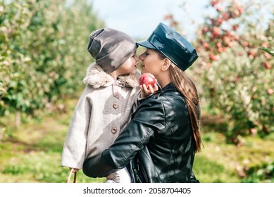 Mom And Her Baby Girl Walking And Picking Apples In The Garden. Harvesting Autumn. Apple Orchard, Wild Garden.